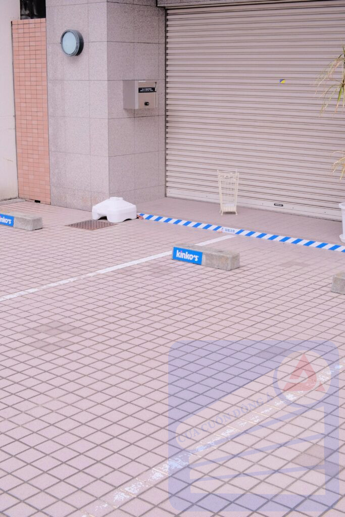 Outdoor tiled parking area with a closed roll-up door and building facade.
