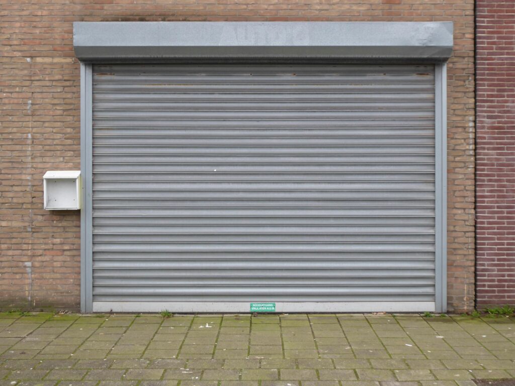 Closed grey metal roller shutter door for security and protection in urban exterior.