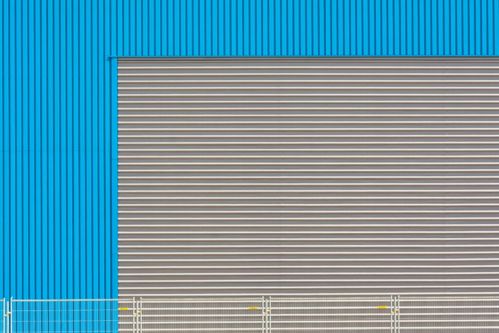 Blue industrial building facade with shutter door, showcasing modern architecture.